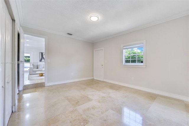 empty room with ornamental molding and a textured ceiling