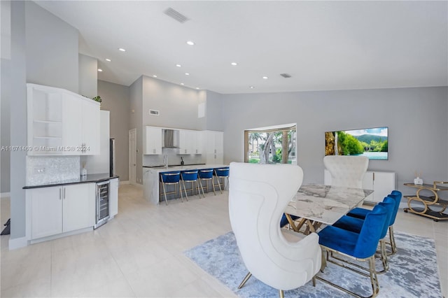 dining area featuring light tile patterned flooring, sink, wine cooler, and high vaulted ceiling