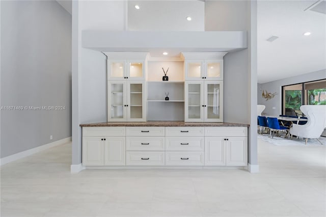 bar with dark stone counters and white cabinetry