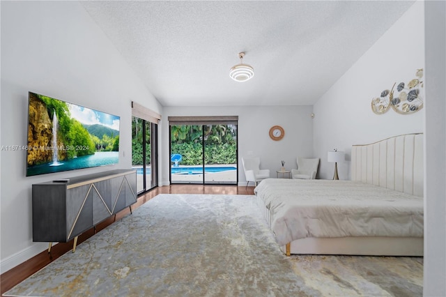 bedroom with vaulted ceiling, hardwood / wood-style flooring, access to exterior, and a textured ceiling