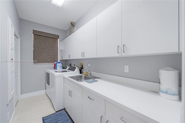 washroom featuring a textured ceiling, washing machine and dryer, sink, and cabinets