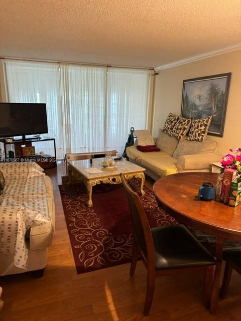 5830 NW 64th Ave Unit 104, Tamarac, FL 33319 - living room with wood finished floors, a textured ceiling, and crown molding