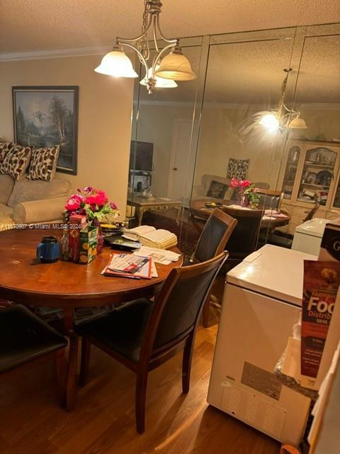 5830 NW 64th Ave Unit 104, Tamarac, FL 33319 - dining space with ornamental molding, dark wood-style flooring, a textured ceiling, and washer / dryer