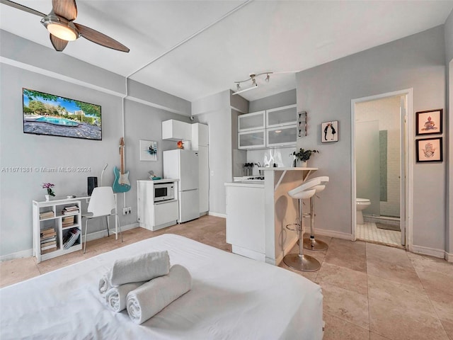 tiled bedroom with ceiling fan, white refrigerator, and connected bathroom