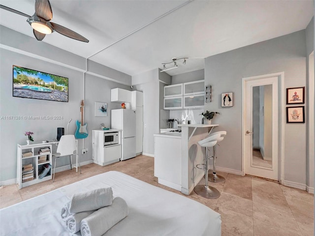 interior space with light tile patterned floors, ceiling fan, and white fridge