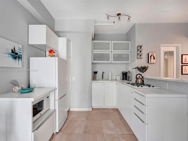 kitchen with white appliances, white cabinetry, and sink