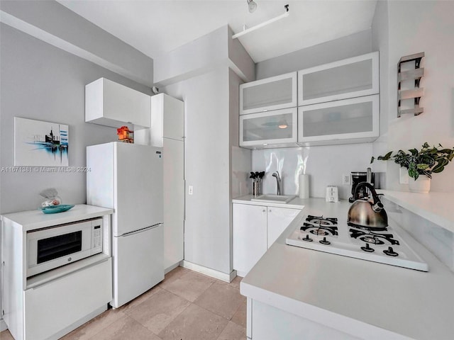 kitchen featuring white appliances, white cabinetry, light tile patterned flooring, and sink