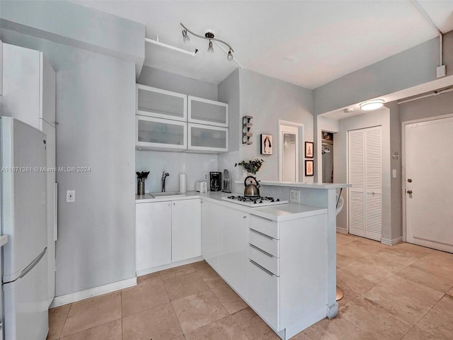 kitchen with white appliances, white cabinetry, sink, and kitchen peninsula