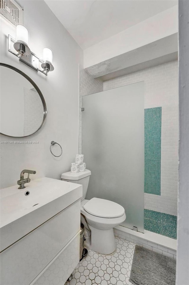 bathroom featuring a tile shower, vanity, toilet, and tile patterned floors