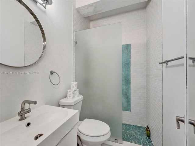 bathroom with tiled shower, vanity, and toilet