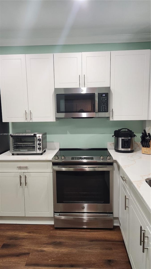 kitchen with light stone counters, white cabinets, stainless steel appliances, and dark hardwood / wood-style flooring