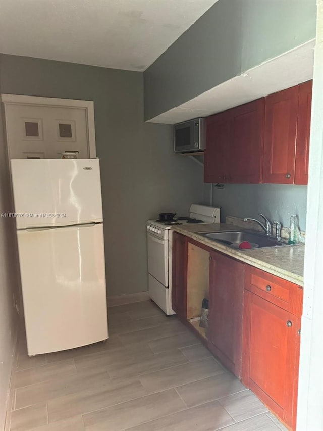 kitchen with light wood-type flooring, white appliances, and sink