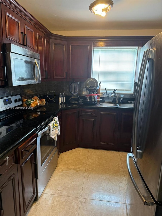 kitchen featuring light tile patterned flooring, sink, stainless steel appliances, backsplash, and dark stone countertops