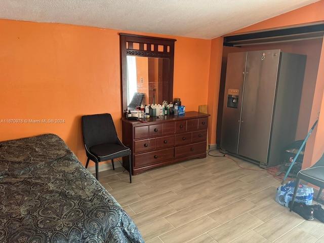 bedroom featuring a textured ceiling and stainless steel fridge