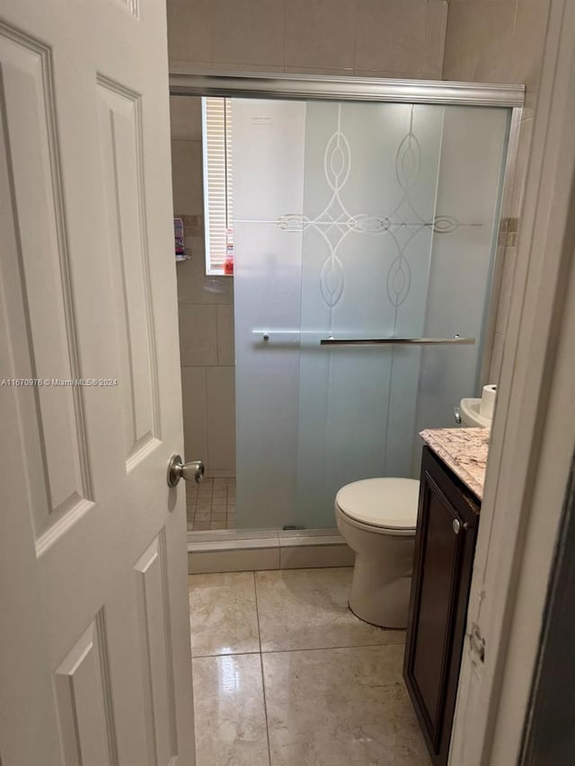 bathroom with tile patterned flooring, walk in shower, vanity, and toilet