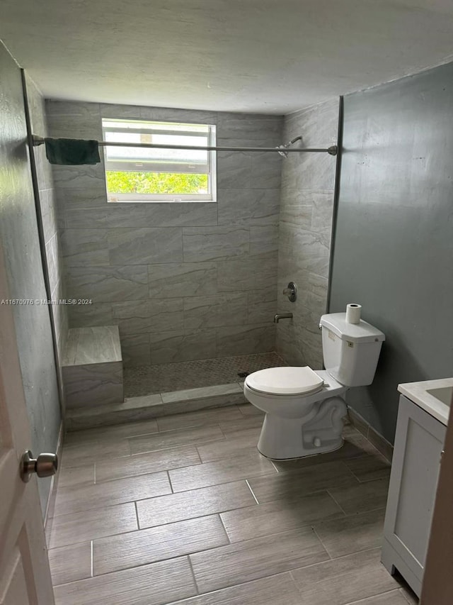 bathroom with tiled shower, vanity, and toilet