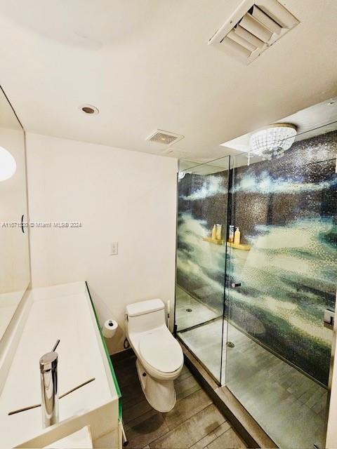 bathroom featuring hardwood / wood-style floors, toilet, and a shower