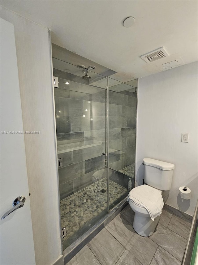 bathroom with toilet and a shower with door