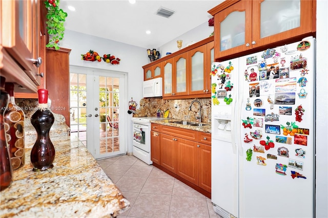 kitchen with white appliances, sink, light tile patterned floors, and light stone counters