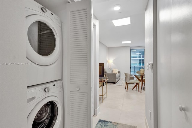 laundry area with stacked washer / dryer and light tile patterned floors