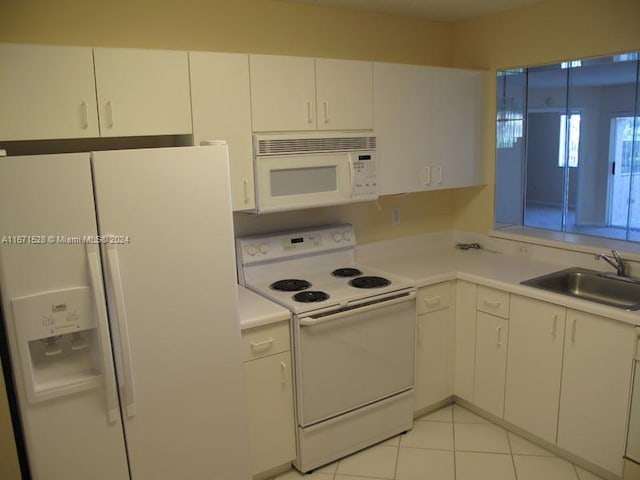 kitchen with light tile patterned floors, sink, white appliances, and white cabinetry