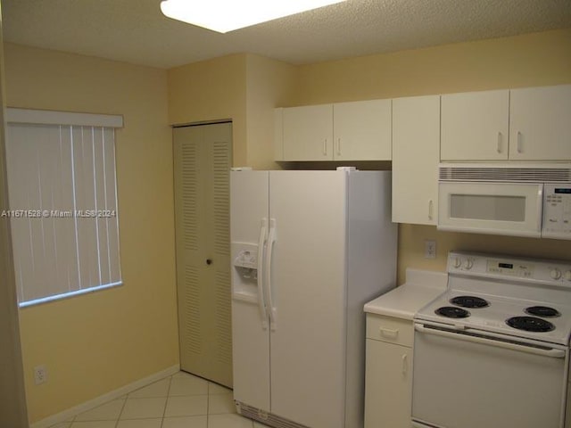 kitchen with white cabinets, white appliances, a textured ceiling, and light tile patterned floors