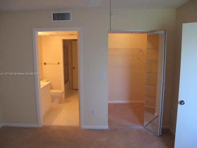 unfurnished bedroom featuring connected bathroom, a closet, and carpet flooring