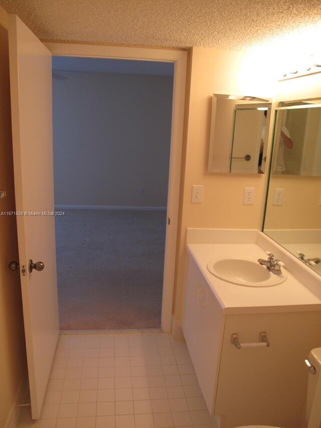 9511 Weldon Cir Unit G402, Tamarac, FL 33321 - bathroom featuring vanity, toilet, a textured ceiling, tile patterned floors, and baseboards