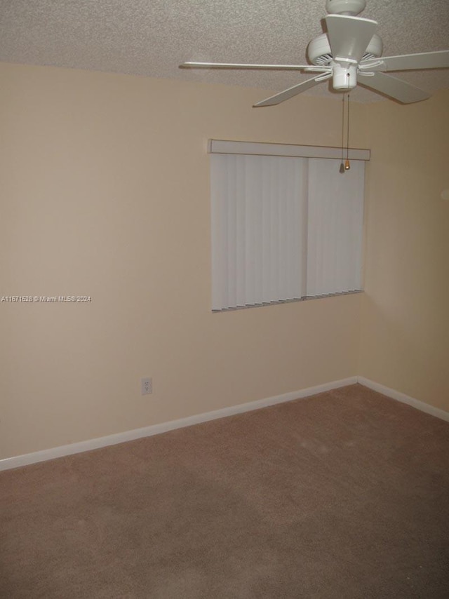 carpeted spare room featuring a textured ceiling and ceiling fan