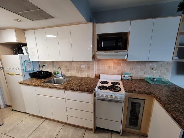 kitchen featuring white appliances, white cabinets, sink, dark stone countertops, and extractor fan