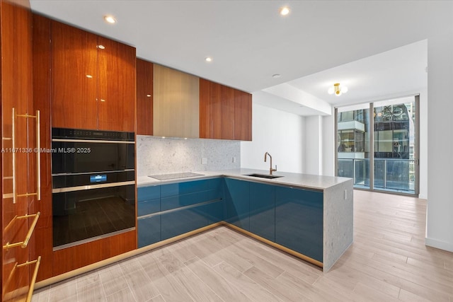 kitchen featuring black appliances, expansive windows, sink, light wood-type flooring, and tasteful backsplash