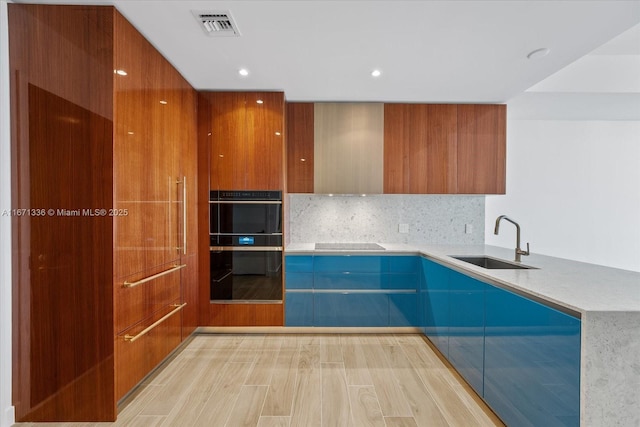 kitchen with decorative backsplash, sink, black appliances, and light hardwood / wood-style flooring