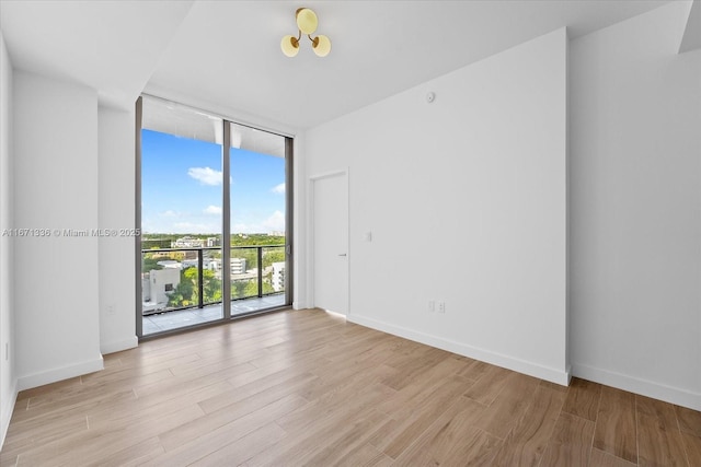 empty room with a wall of windows and light hardwood / wood-style flooring