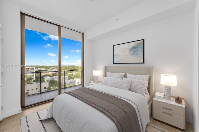 bedroom featuring access to outside, light hardwood / wood-style flooring, and floor to ceiling windows