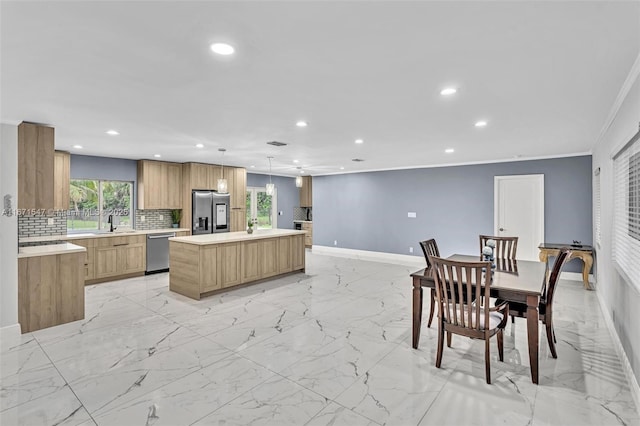 kitchen with crown molding, hanging light fixtures, stainless steel appliances, tasteful backsplash, and a kitchen island