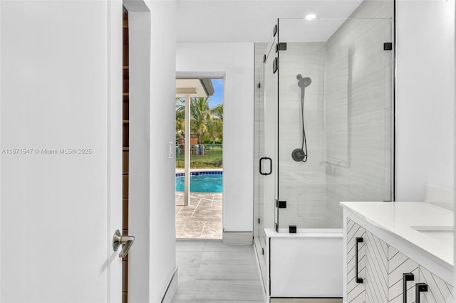 bathroom featuring a shower with door and vanity