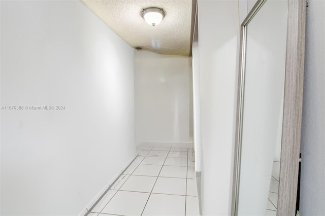 hallway featuring a textured ceiling and light tile patterned floors