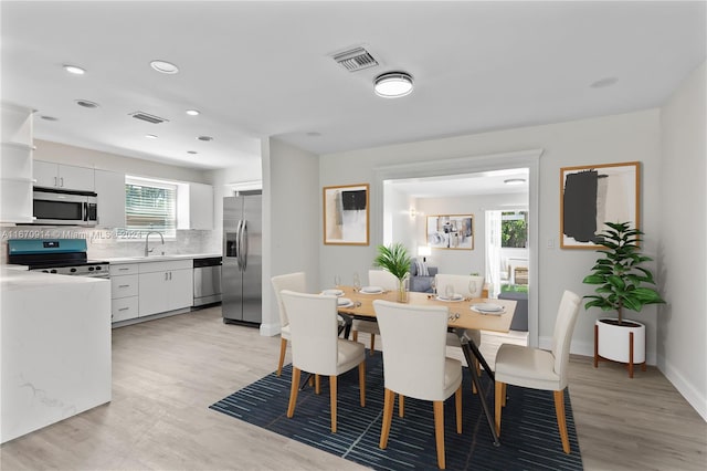 dining area featuring light hardwood / wood-style floors, a healthy amount of sunlight, and sink