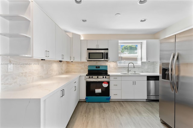 kitchen with light hardwood / wood-style floors, white cabinetry, backsplash, stainless steel appliances, and sink