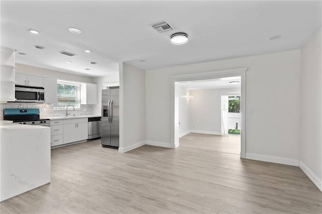 kitchen with appliances with stainless steel finishes, white cabinetry, and a wealth of natural light