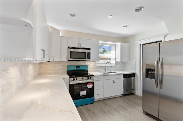 kitchen with light wood-type flooring, sink, white cabinets, stainless steel appliances, and backsplash