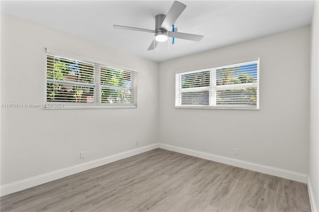 spare room featuring light wood-type flooring, ceiling fan, and plenty of natural light