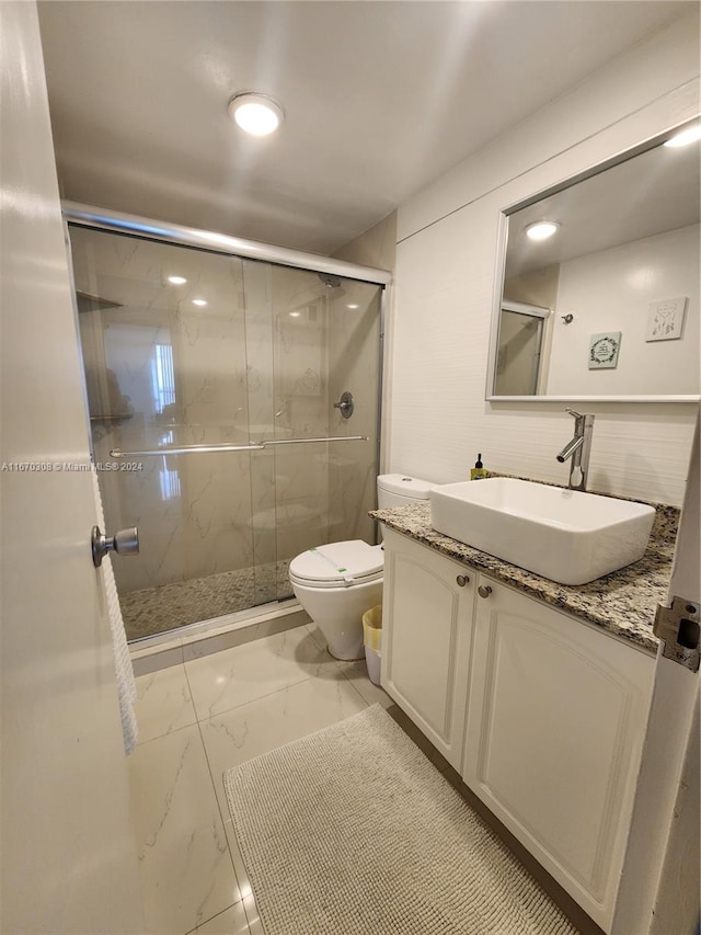 bathroom with a shower with shower door, vanity, and toilet