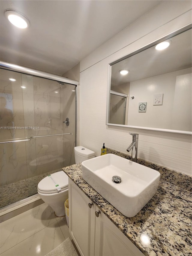 bathroom with toilet, vanity, and a shower with shower door