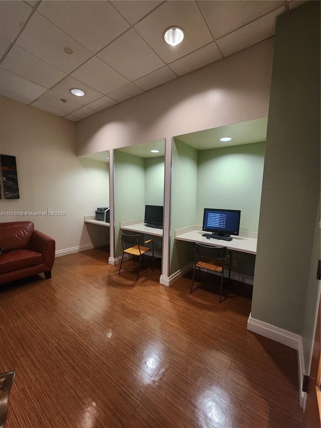 office featuring a paneled ceiling, hardwood / wood-style floors, and built in desk