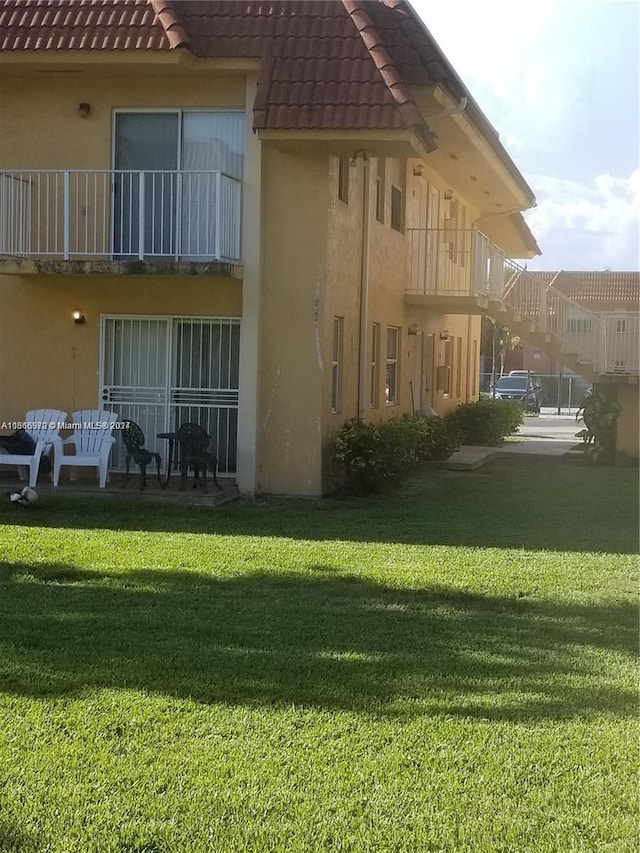 rear view of property with a lawn and a balcony