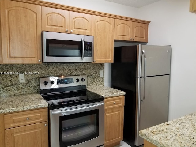 kitchen with light stone counters, appliances with stainless steel finishes, and tasteful backsplash