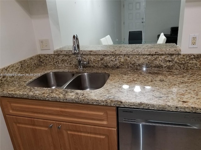 kitchen with dishwasher, sink, and light stone counters