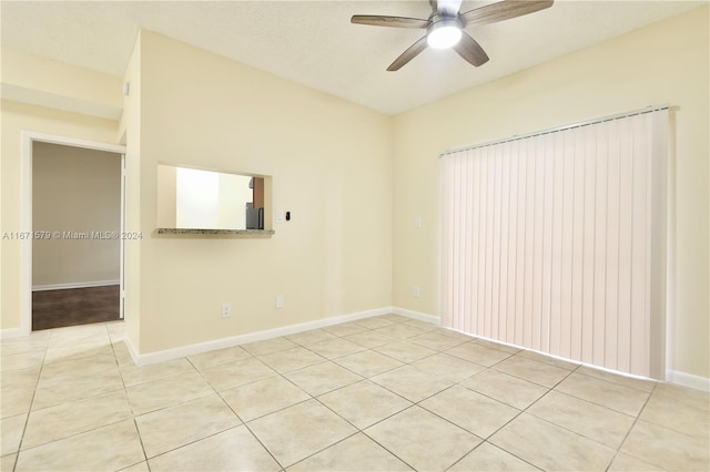 tiled spare room featuring ceiling fan