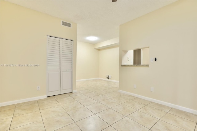 unfurnished room featuring light tile patterned flooring and a textured ceiling